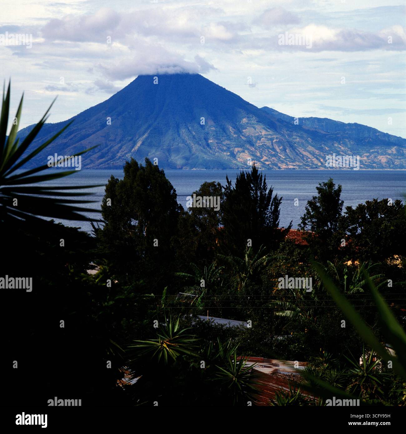 Blick über den Atitlán-See auf den teils wolkenverhangenen Vulkan San Pedro. Guatemala, um 1980. Banque D'Images