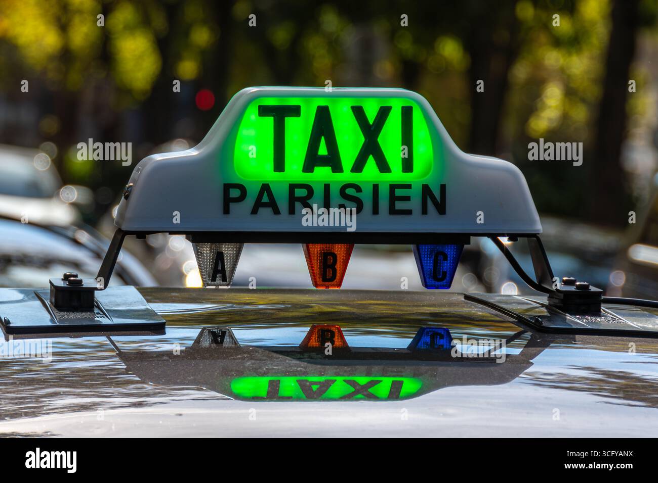 Gros plan du panneau lumineux sur le toit d'un taxi parisien avec le mot « TAXI » allumé en vert (taxi gratuit) à une station de taxis dans une rue de Paris Banque D'Images
