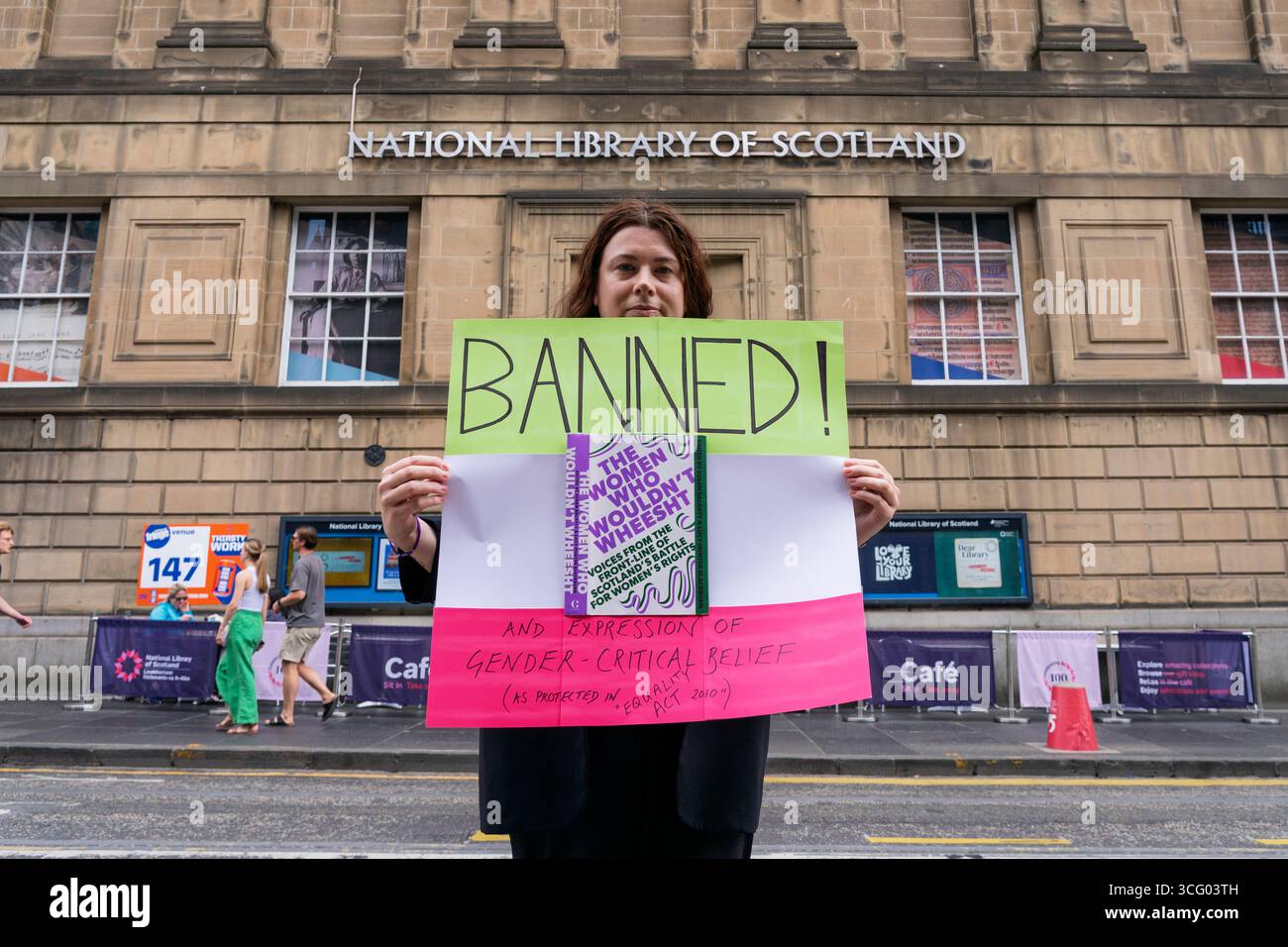 Édimbourg, Écosse, Royaume-Uni. 25 août 2025. Une femme tient une pancarte devant la Bibliothèque nationale d’Écosse pour protester contre l’exclusion du livre The Women Who Would Not Wheesht de son exposition du centenaire Dear Library. La bibliothèque a été critiquée pour avoir omis le livre (bien qu’ayant reçu suffisamment de votes du public pour être inclus) qui contient des essais d’auteurs féminins détaillant leurs luttes et leurs expériences dans la lutte pour les droits des femmes. Iain Masterton/Alamy Live News Banque D'Images