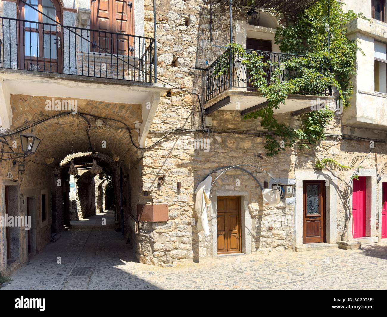 Île de Chios, Grèce. Plante grimpante et arc de pierre dans une ruelle pavée, village médiéval de Mesta, architecture traditionnelle. Banque D'Images