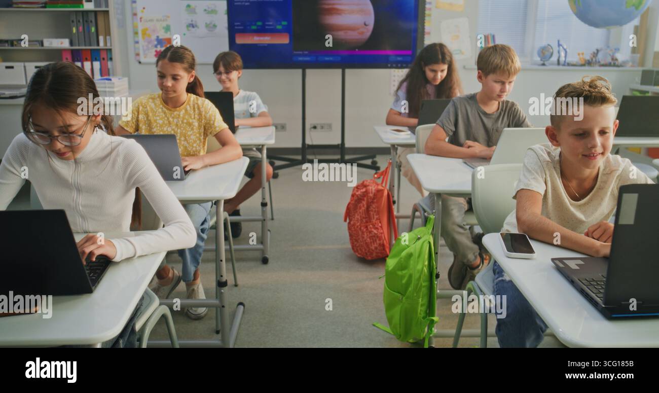 Élèves de l'école primaire travaillant sur des projets créatifs sur des ordinateurs portables, pratiquant les compétences numériques en classe d'art. Écran numérique montrant le logiciel ai pour la création d'images. Apprentissage interactif STEM. Dolly Shot Banque D'Images