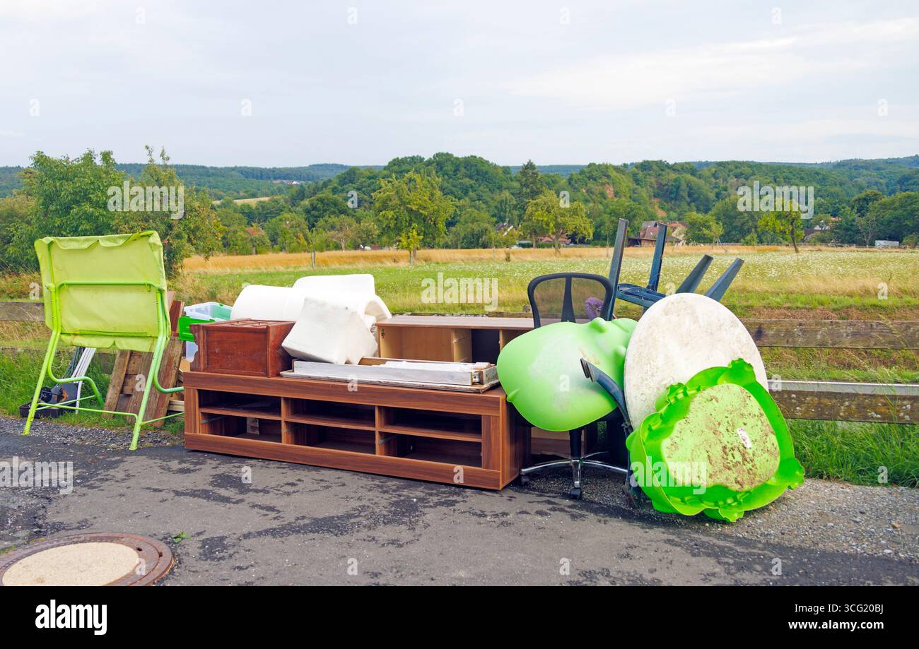 Meubles et articles ménagers jetés polluant un beau paysage naturel, soulignant le problème du déversement illégal Banque D'Images