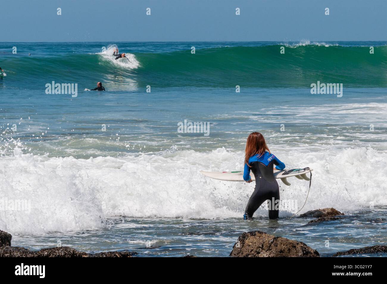 MALIBU, CALIFORNIE, États-Unis : une surfeuse entre dans l'eau en anticipant une marée montante et des sets de 6 à 8 pieds, avec quelques vagues aussi grandes que 12 pieds, sur un soleil Banque D'Images