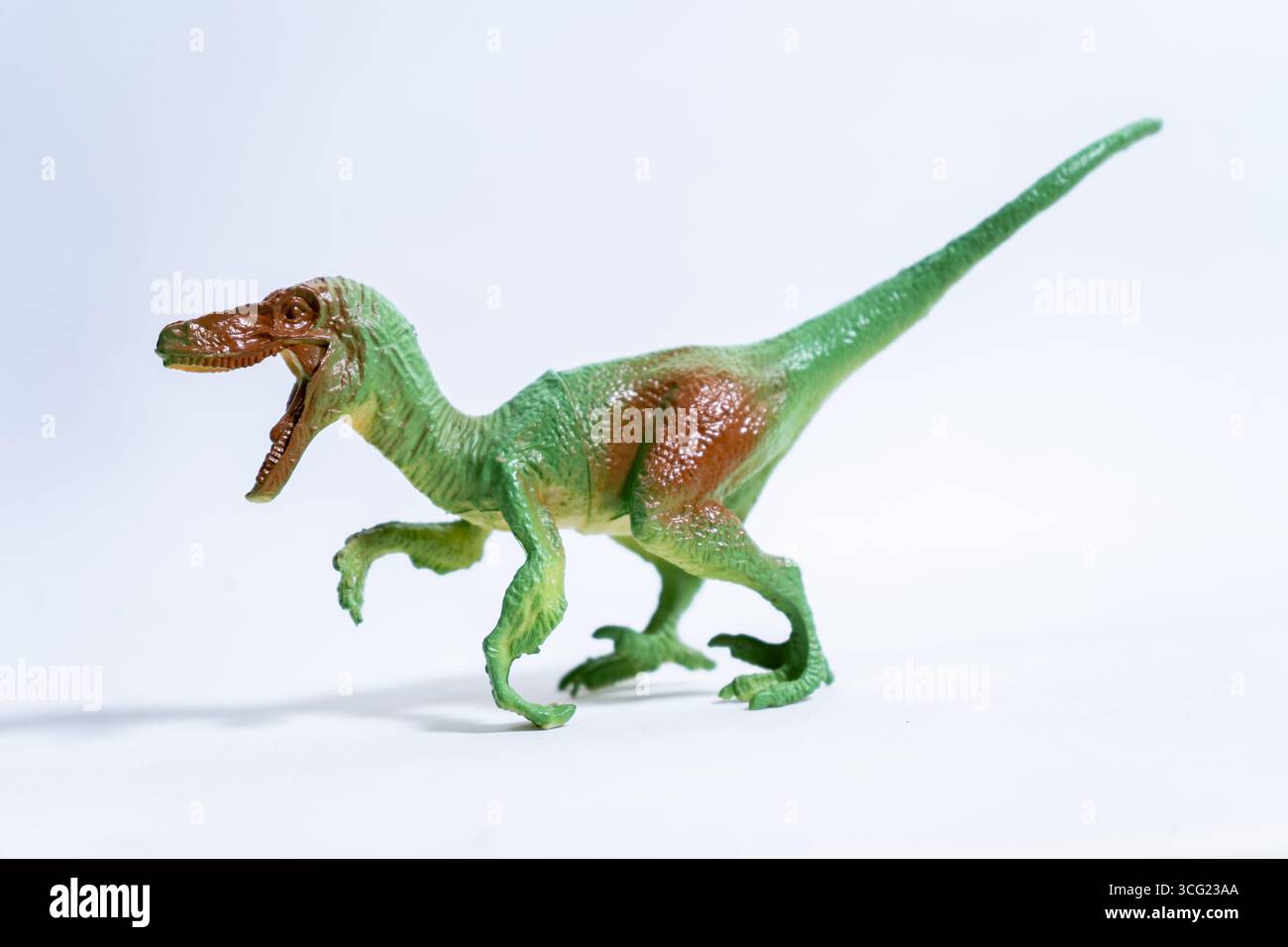 Jouet dinosaure vélociraptor en plastique fonctionnant sur un fond blanc sans couture Banque D'Images