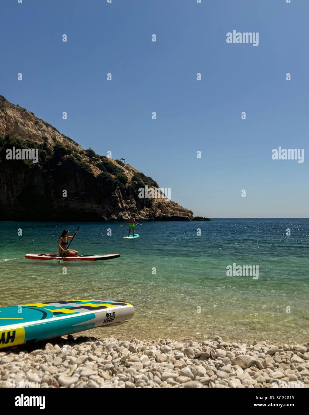 Paddleboarders profitant d'une journée ensoleillée dans un endroit côtier serein Banque D'Images