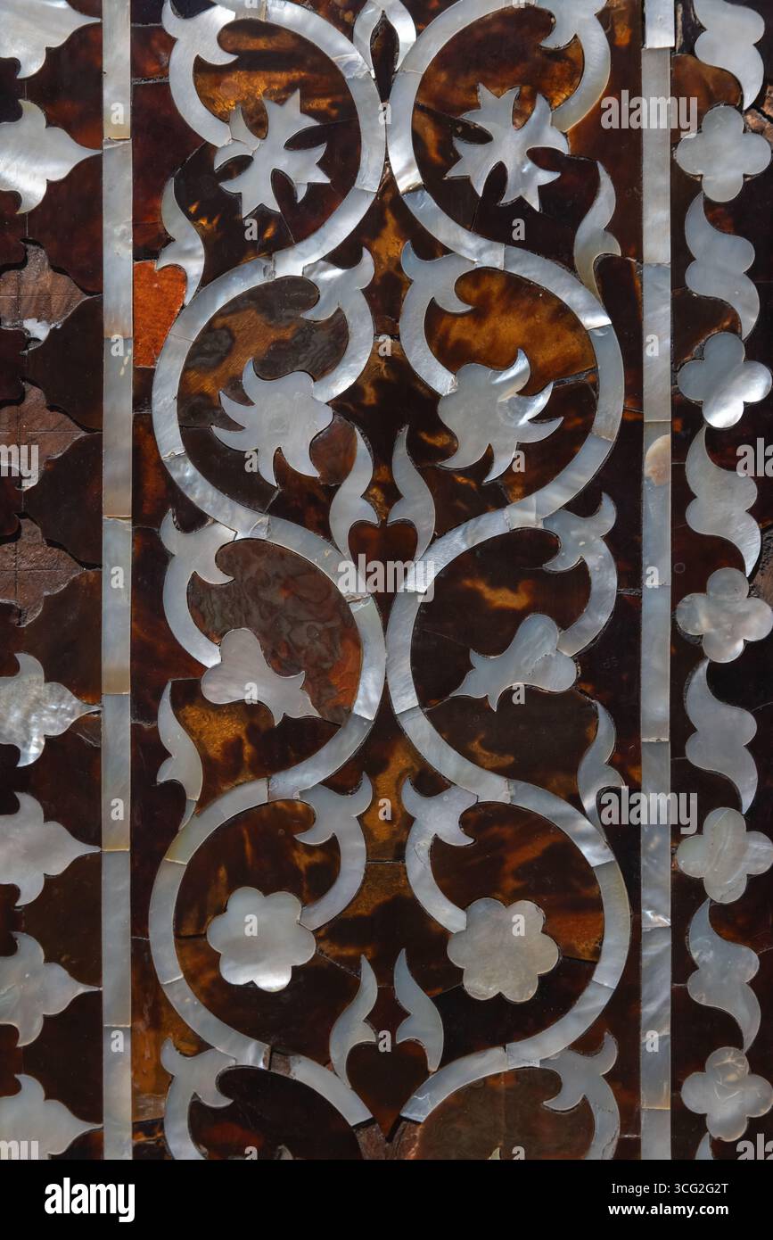 Élégant motif de nacre incrusté sur une surface texturée richement colorée mettant en valeur le design complexe d'une décoration de meubles anciens Banque D'Images