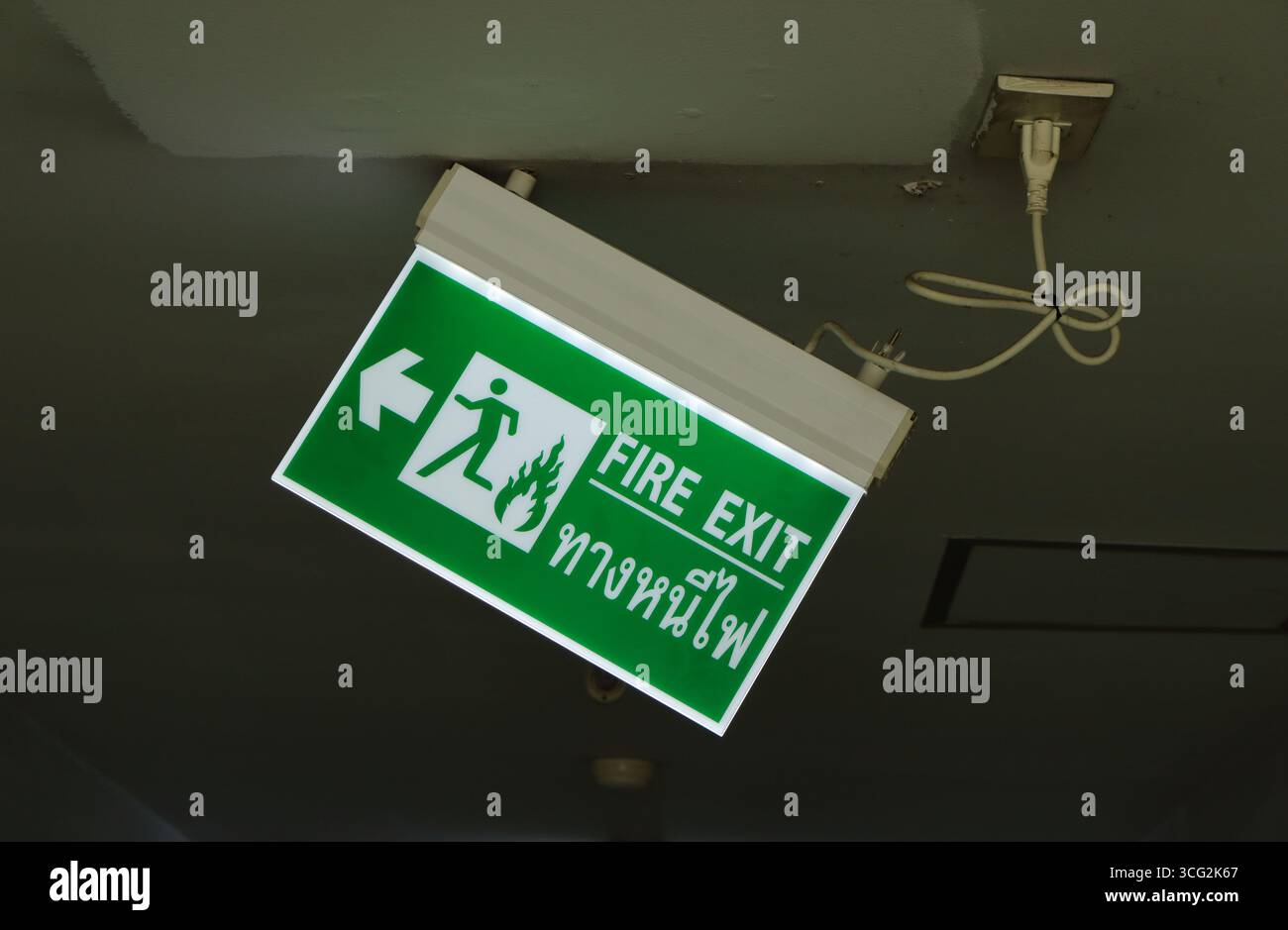 Gros plan panneau de signalisation de sortie de secours avec une vis détachée, le panneau est incliné et presque tombé en raison de la vis desserrée Banque D'Images