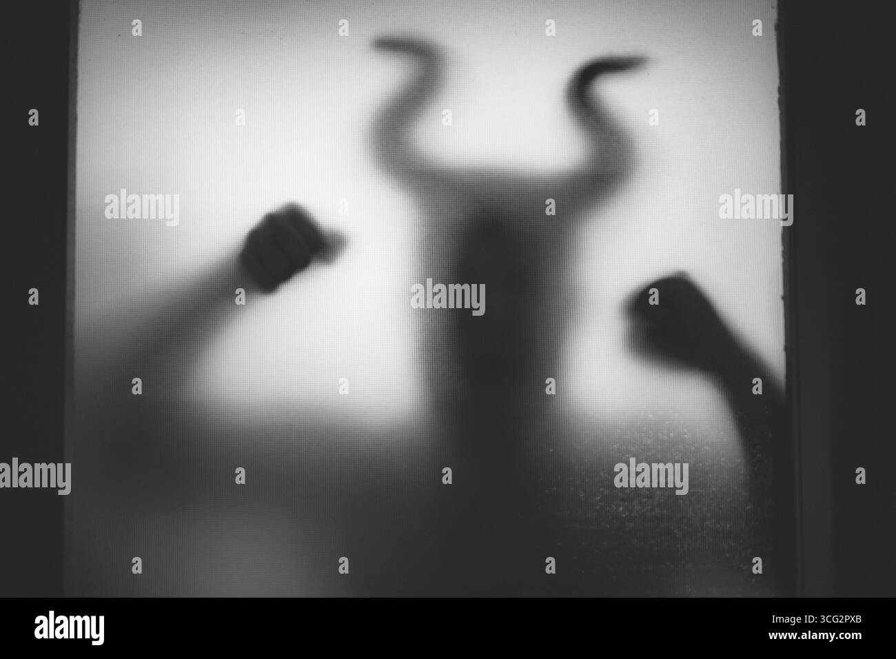 Figure effrayante avec des cornes dans le noir, derrière la fenêtre. Fond d'Halloween Banque D'Images