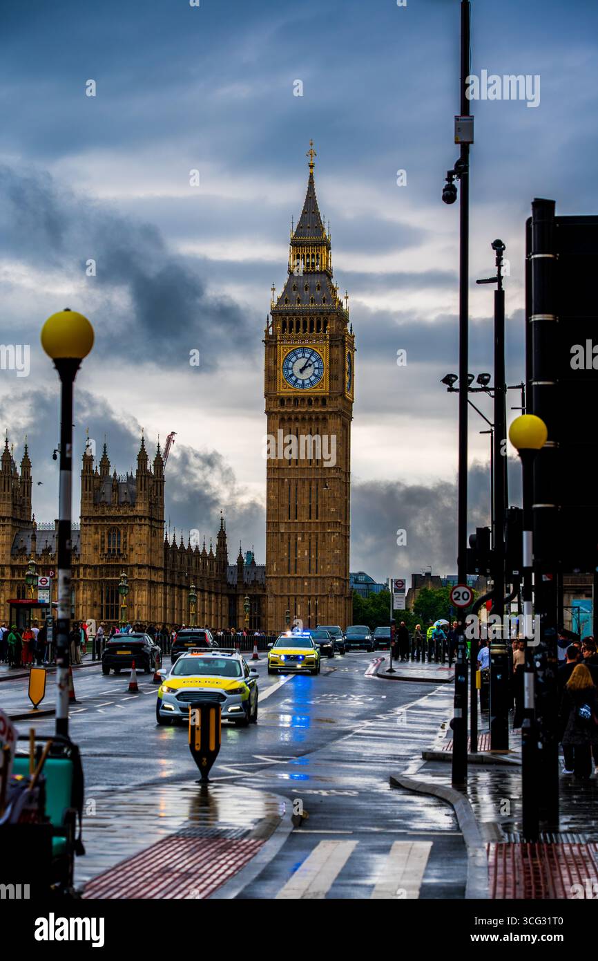 Vue emblématique de la tour de l'horloge Big Ben à Westminster avec la circulation, les voitures de police et les piétons sur une rue pluvieuse de Londres sous des nuages spectaculaires Banque D'Images