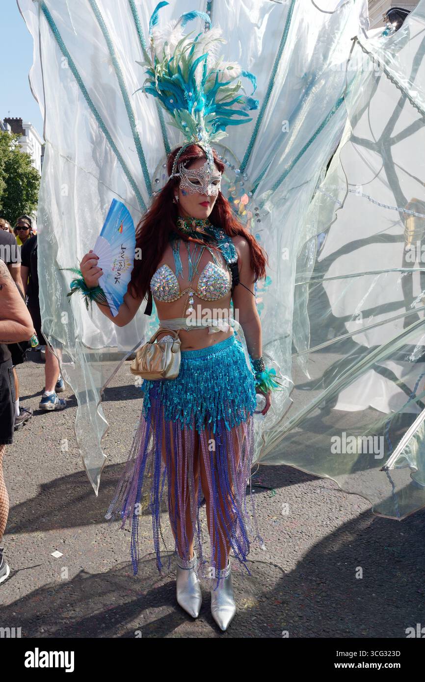 Femme sulfureuse avec coiffe/coiffe bleue et masque argenté et tenue de bikini pendant le Carnaval de Notting Hill, Londres. Angleterre 25 août 2025 Banque D'Images