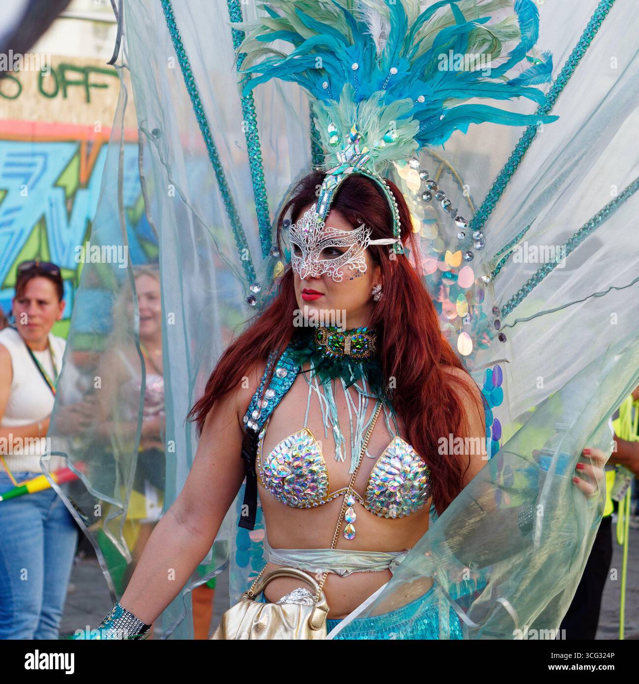 Femme sulfureuse avec coiffe/coiffe bleue et masque argenté et tenue de bikini pendant le Carnaval de Notting Hill, Londres. Angleterre 25 août 2025 Banque D'Images