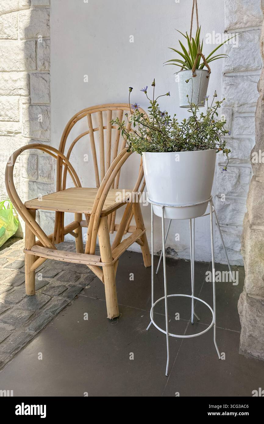 décor de patio boho minimaliste confortable avec plantes en pot et chaise en bois rond contre un mur de pierre. Concepts de jardinage à la maison, de relaxation et respectueux de l'environnement l Banque D'Images