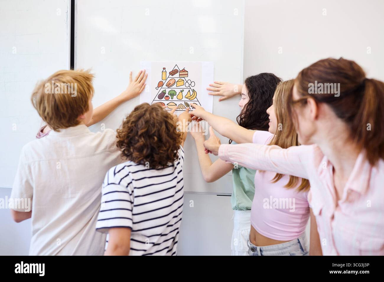 Un groupe d'élèves discutant de façon interactive des concepts de nutrition et de pyramide alimentaire en classe. Banque D'Images