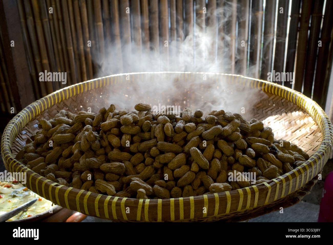 Kacang Rebus, cacahuètes bouillies chaudes et fumées dans un récipient en bambou tissé. Banque D'Images