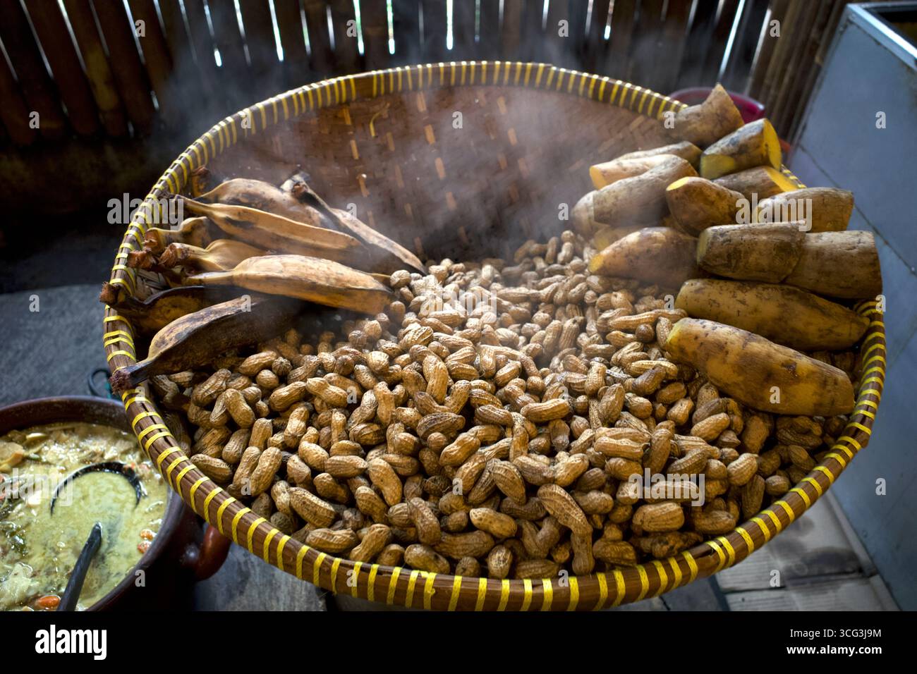 Kacang Rebus, cacahuètes bouillies chaudes et fumées dans un récipient en bambou tissé. Banque D'Images