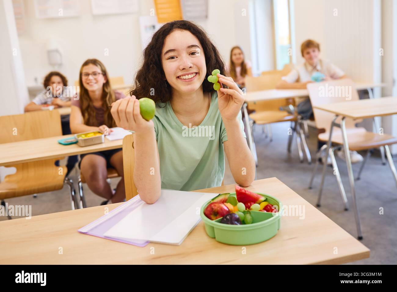 Un groupe d'élèves dans une salle de classe déguste des fruits frais, favorisant des habitudes alimentaires saines dans un environnement éducatif. L'ambiance est joyeuse, pro Banque D'Images