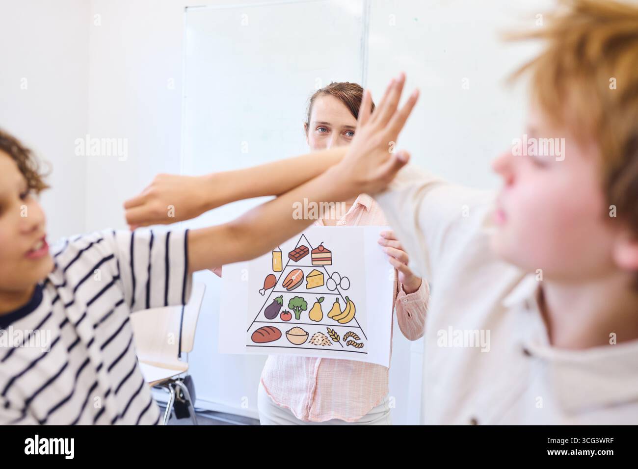 Les élèves participent à une discussion sur la nutrition saine dans une salle de classe à l'aide d'aides visuelles. Banque D'Images