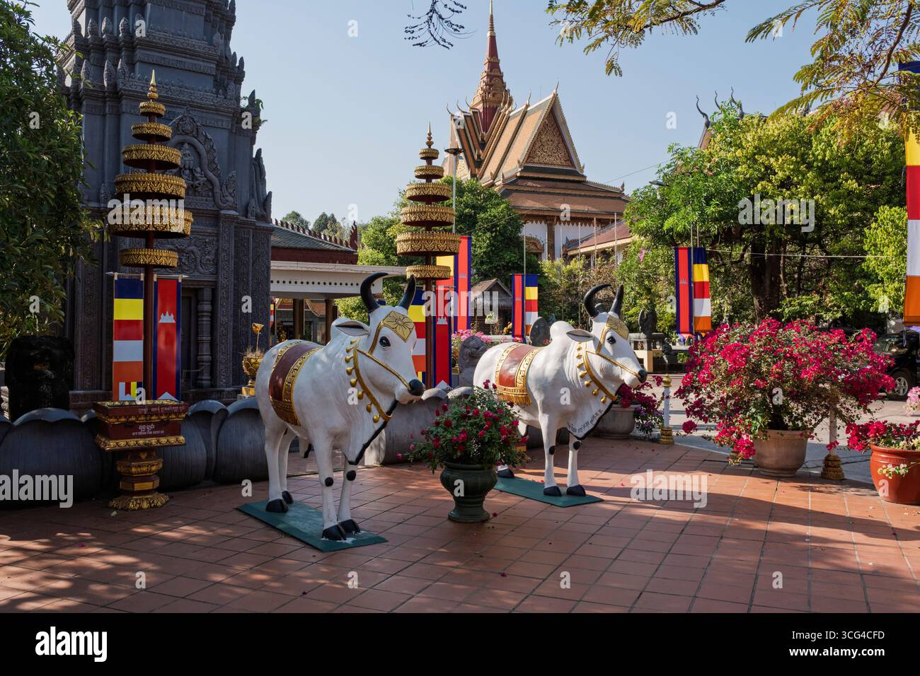 Une paire de vaches blanches sacrées représentées dans l'une des nombreuses sculptures colorées du complexe du temple bouddhiste Wat Preah Prom Rath, Siem Reap, Cambodge Banque D'Images