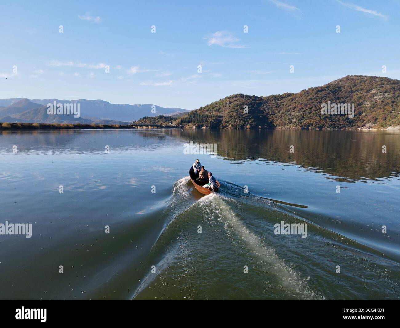 Lac de Skadar (TGD), Monténégro – 2020/11/08 : réveil matinal en bateau sur des eaux calmes près de Virpazar, encadré par des crêtes montagneuses et des pentes boisées. Banque D'Images