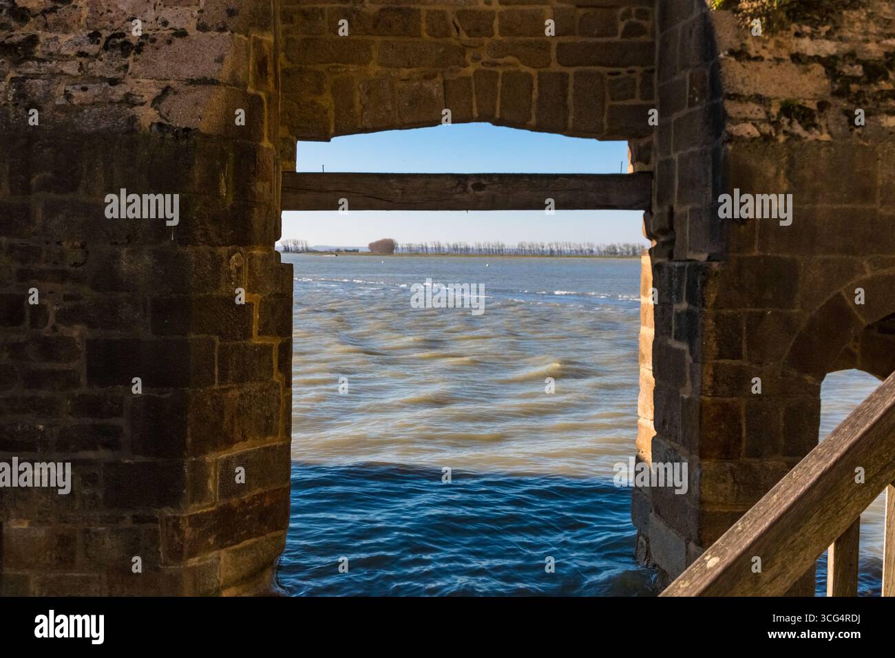 Par la première porte d’entrée du Mont-Saint-Michel, la porte de l’avancée, la vue s’ouvre sur la baie remplie de marées au-delà. Banque D'Images