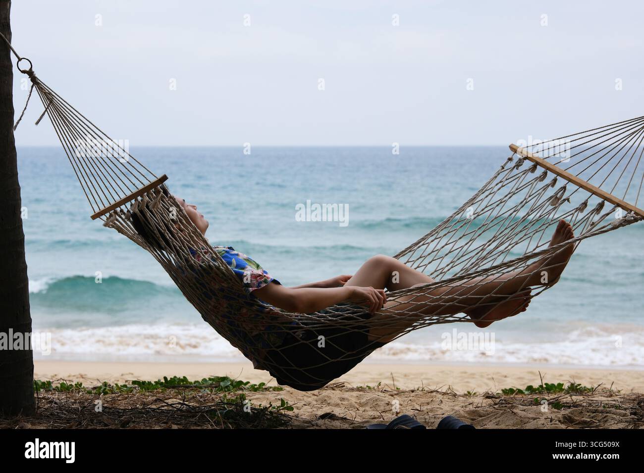 Homme se détend dans un hamac sur la plage à Sanya, Hainan, Chine Banque D'Images