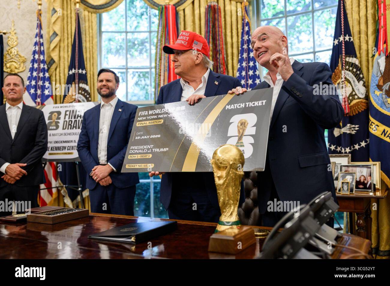 Le président Donald J. Trump et le président de la FIFA Gianni Infantino présentent un ticket de match symbolique surdimensionné pour la finale de la Coupe du monde de la FIFA 2026 lors d’un événement du bureau ovale à la Maison Blanche, Washington, D.C. en août 2025. Le trophée de la Coupe du monde est affiché sur le pupitre présidentiel dans le cadre de la cérémonie d'annonce. Image reproduite avec l'aimable autorisation de la Maison Blanche. Banque D'Images