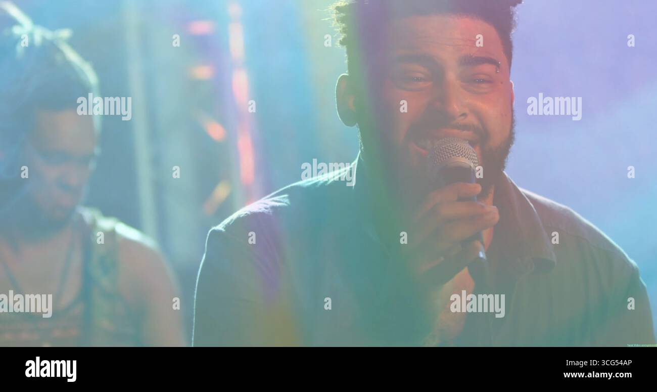 Chanteur masculin chantant microphone à main sur scène de salle de musique, avec des lumières colorées Banque D'Images