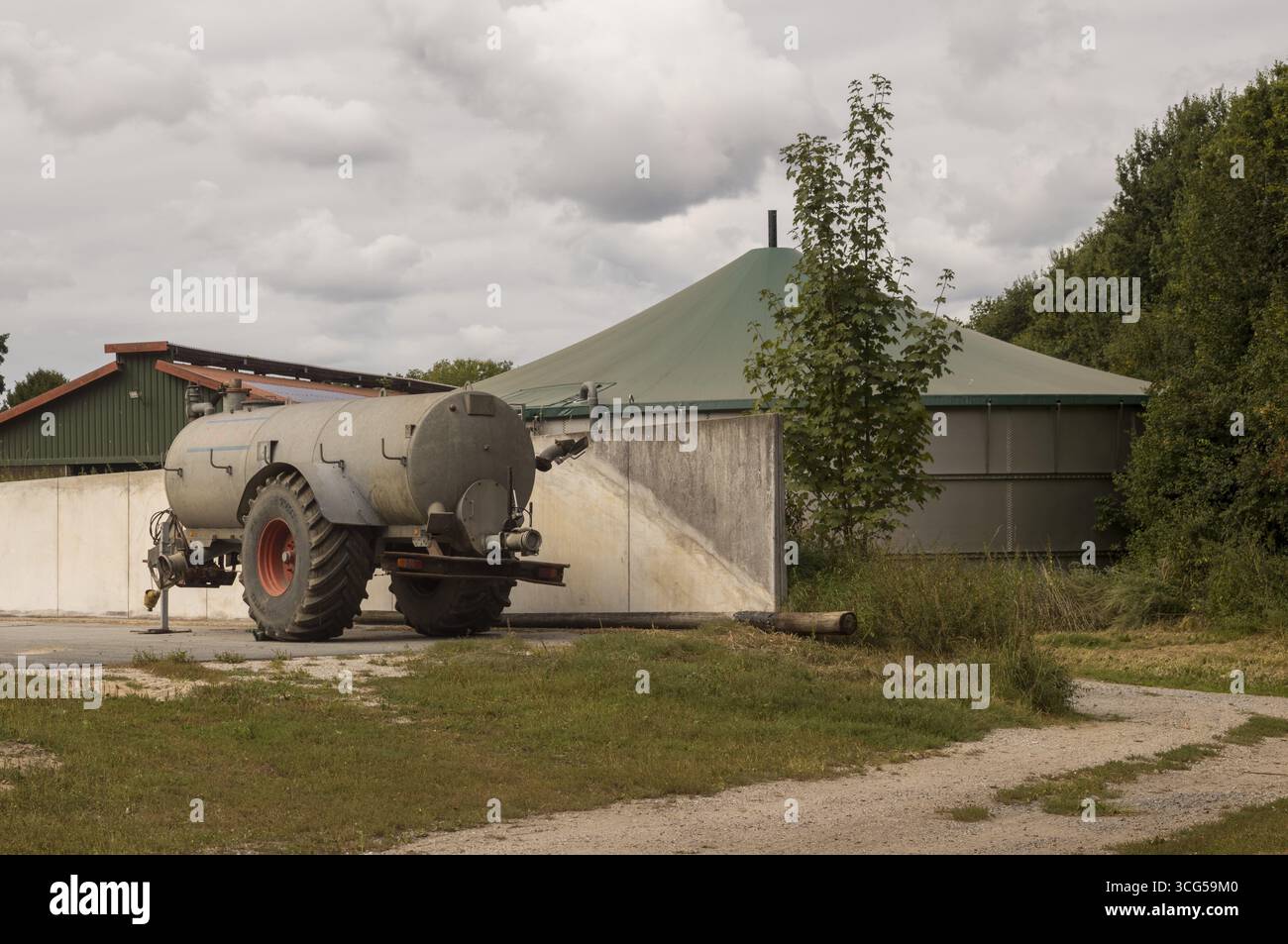 Remorque de camion-citerne garée près de l'usine de biogaz dans une ferme par une journée nuageuse, concept d'agriculture durable Banque D'Images