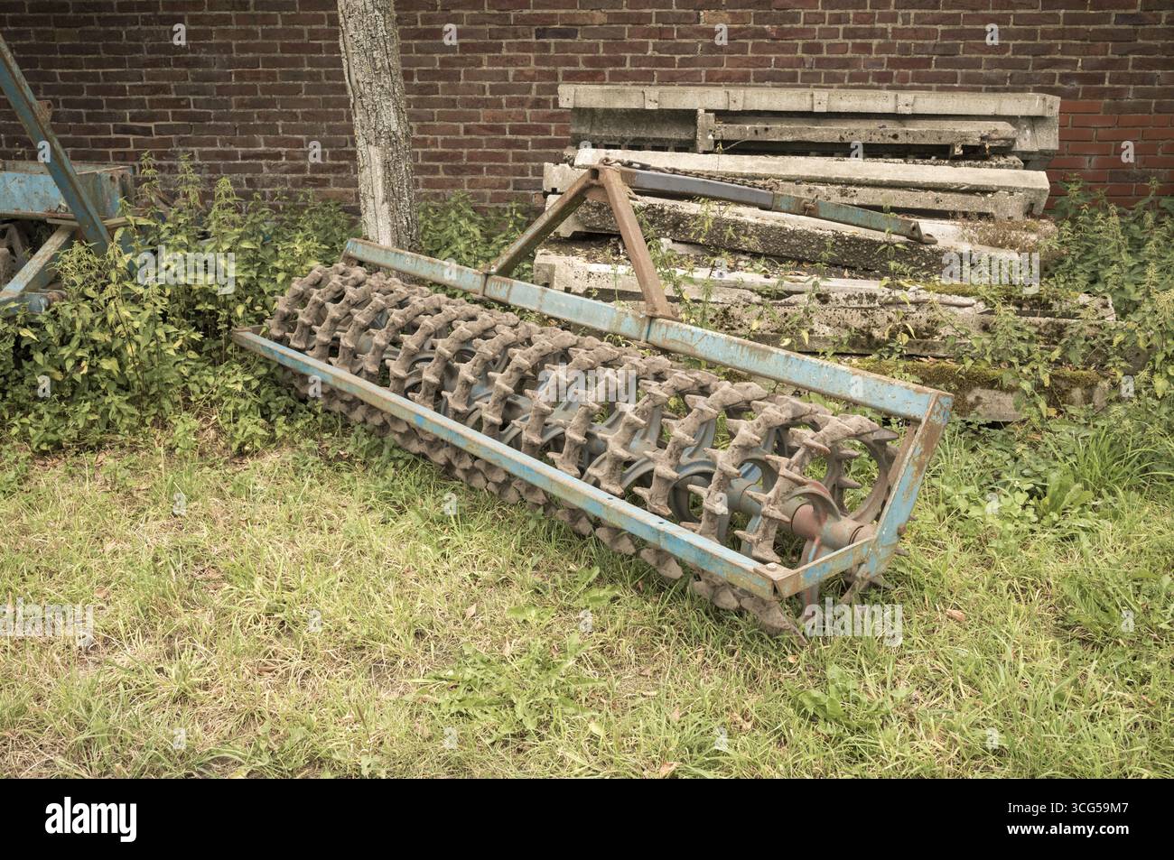 Vieux rouleau cambridge posé sur l'herbe près d'un tas de poutres en béton et un mur de briques Banque D'Images