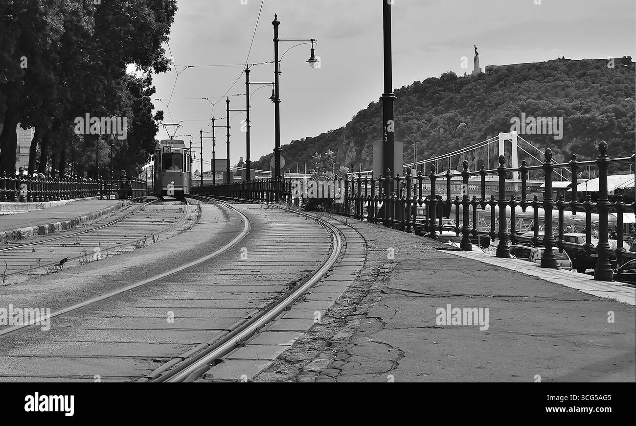 Image en noir et blanc d'un vieux tramway approchant sur les voies de tramway à budapest, avec le pont de la liberté et la colline gellert en arrière-plan Banque D'Images