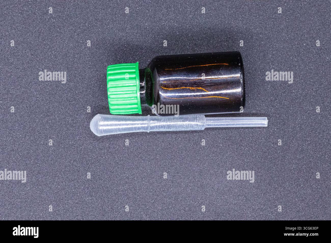 Flacon en verre ambré avec bouchon vert et pipette transparente, idéal pour la distribution d'huiles essentielles, de sérums ou de liquides. Parfait pour les soins de la peau, aromathérapie. Banque D'Images