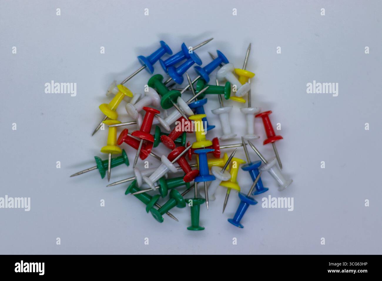 Image en gros plan d'épingles colorées assorties avec des points métalliques pointus sur un fond propre et minimal. Idéal pour le bureau, l'école, l'organisation. Banque D'Images