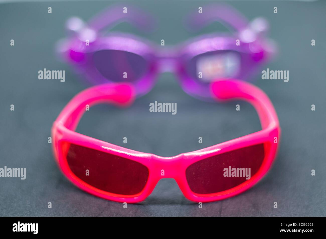 Gros plan de lunettes de sport roses avec verres teintés rouge brillant pour enfants. Banque D'Images