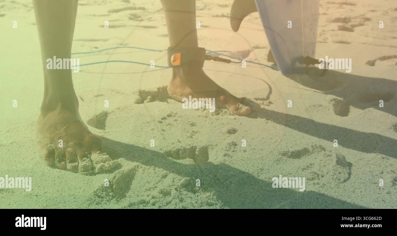 Surfeur debout pieds nus préparant une séance de surf sur la plage ensoleillée, avec laisse de cheville et palme de planche de surf Banque D'Images