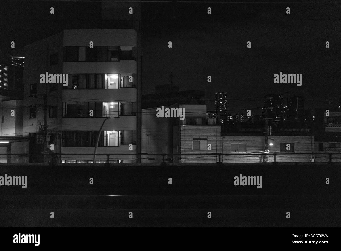 Un paysage urbain la nuit présentant des appartements éclairés et une architecture urbaine sous un ciel sombre. Le contraste souligne l'atmosphère tranquille et contemplative Banque D'Images