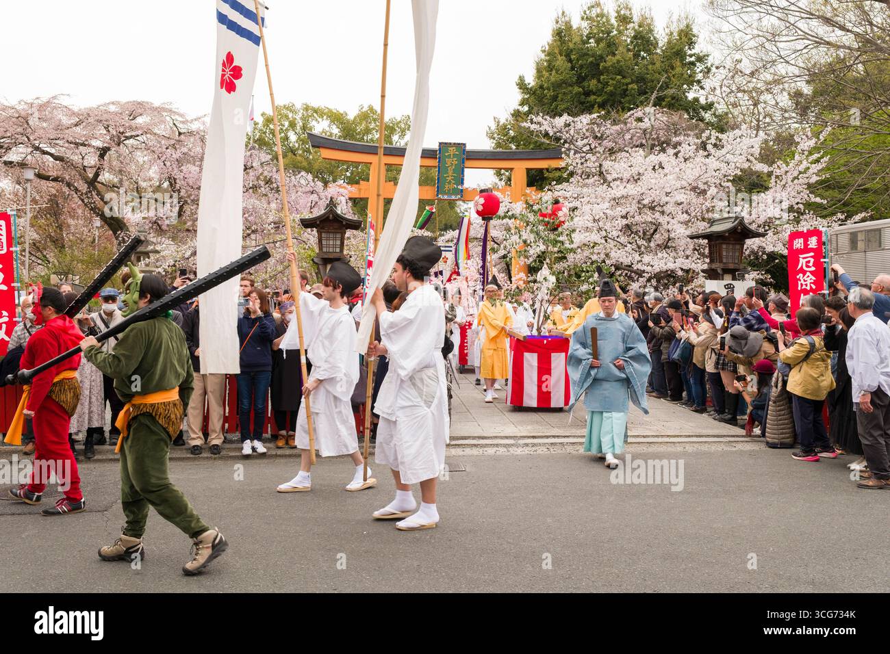 Des hommes portant des masques d'ogre vert et rouge et des costumes tenant des clubs de fer lors de la procession du festival de fleurs de cerisier Ōka-SAI au sanctuaire de Hirano Banque D'Images