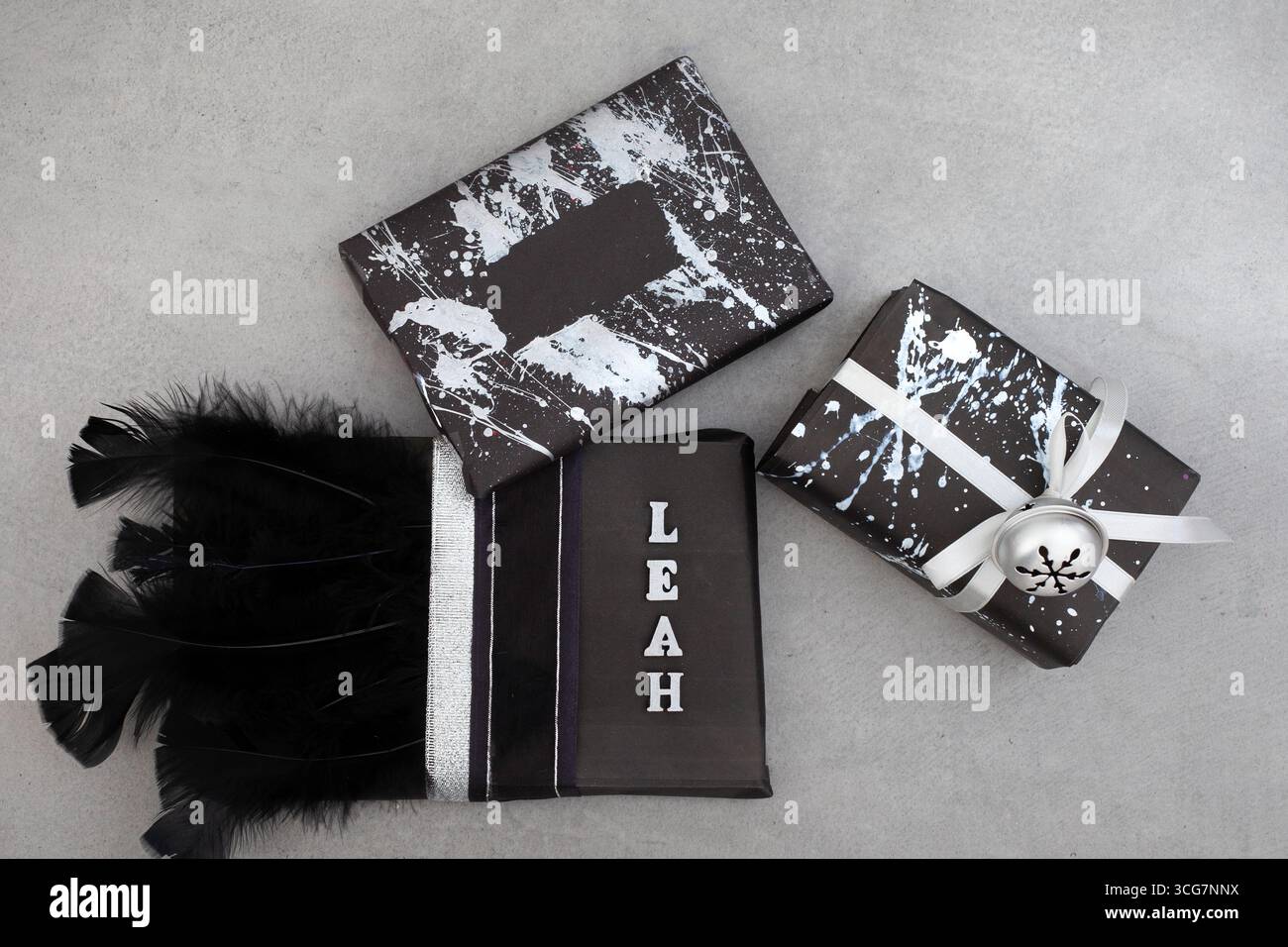 cadeaux enveloppés de noir et décorés de différentes manières. certains ont des éclaboussures de peinture argentée, d'autres ont des rubans, des plumes et des cloches Banque D'Images