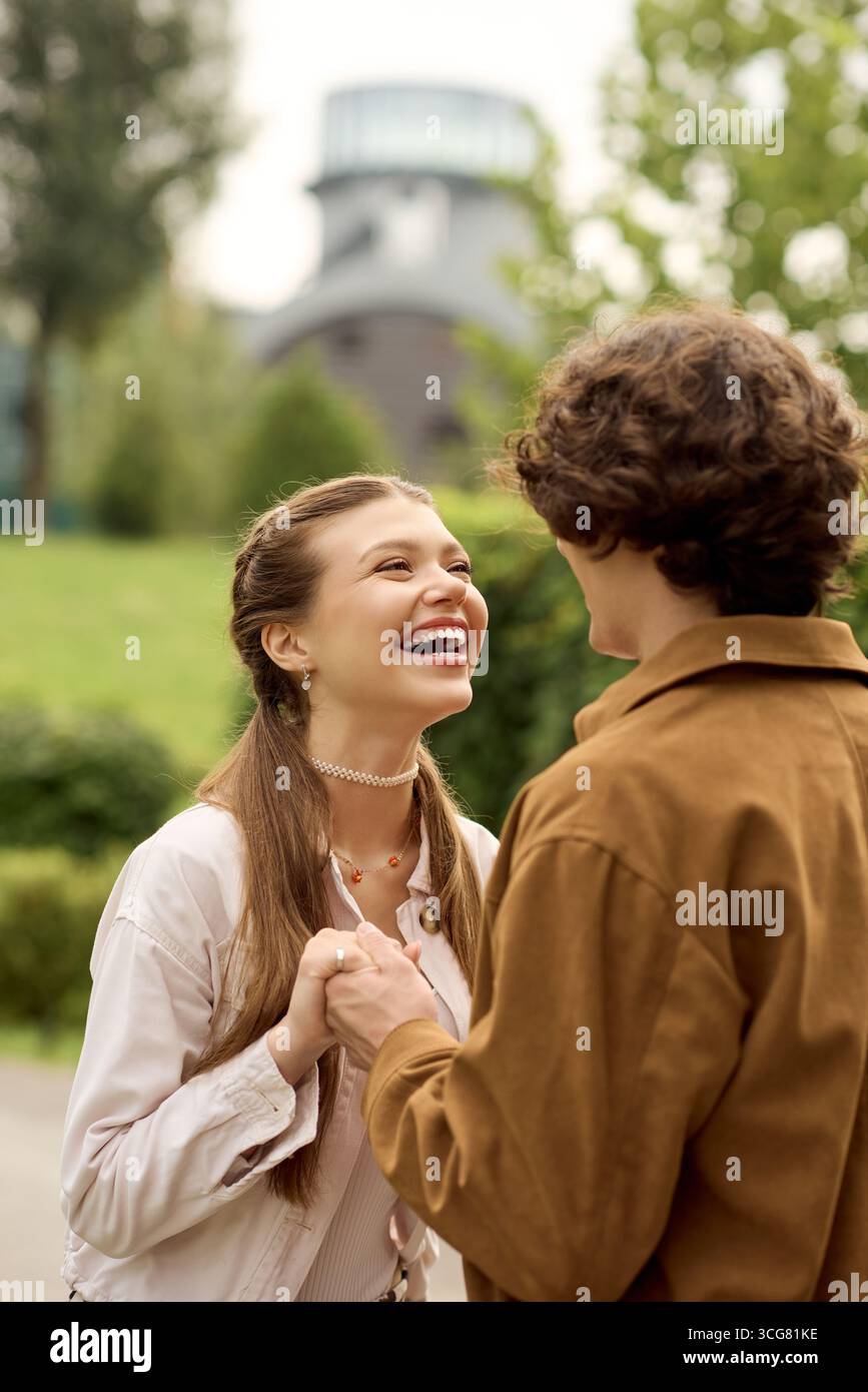 Un jeune couple joyeux partage une agréable promenade dans le parc, enveloppé d'amour et de rire. Banque D'Images