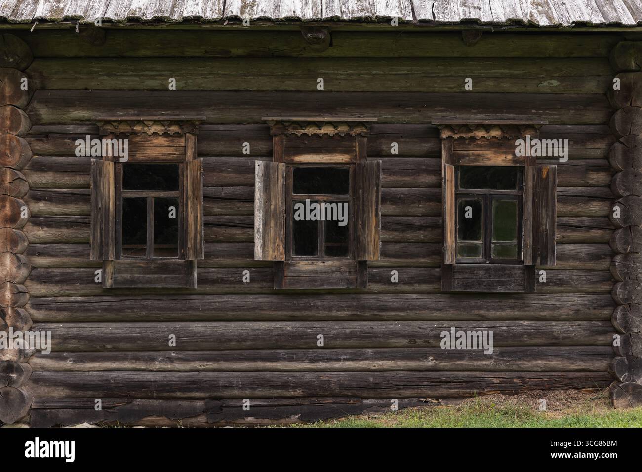 Vue de face d'un mur de maison en rondins russe traditionnel avec trois fenêtres en bois avec volets ouverts, évoquant le charme rustique et un sens de la simplicité A. Banque D'Images