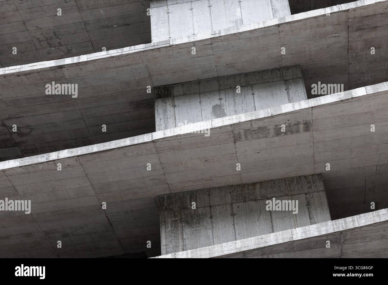 Structure en béton en construction mettant l'accent sur les éléments architecturaux avec des motifs géométriques répétitifs et des surfaces inclinées. Un bâtiment moderne abst Banque D'Images
