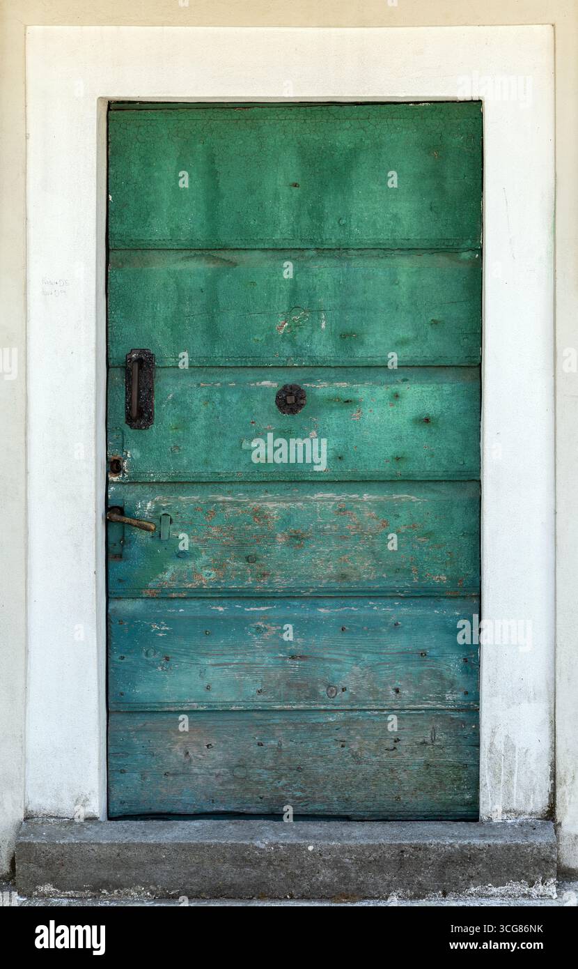 Porte en bois vintage peinte en vert foncé avec des signes d'âge, avec une surface texturée et de la quincaillerie en métal ancien, évoquant le charme rustique et historique. B Banque D'Images