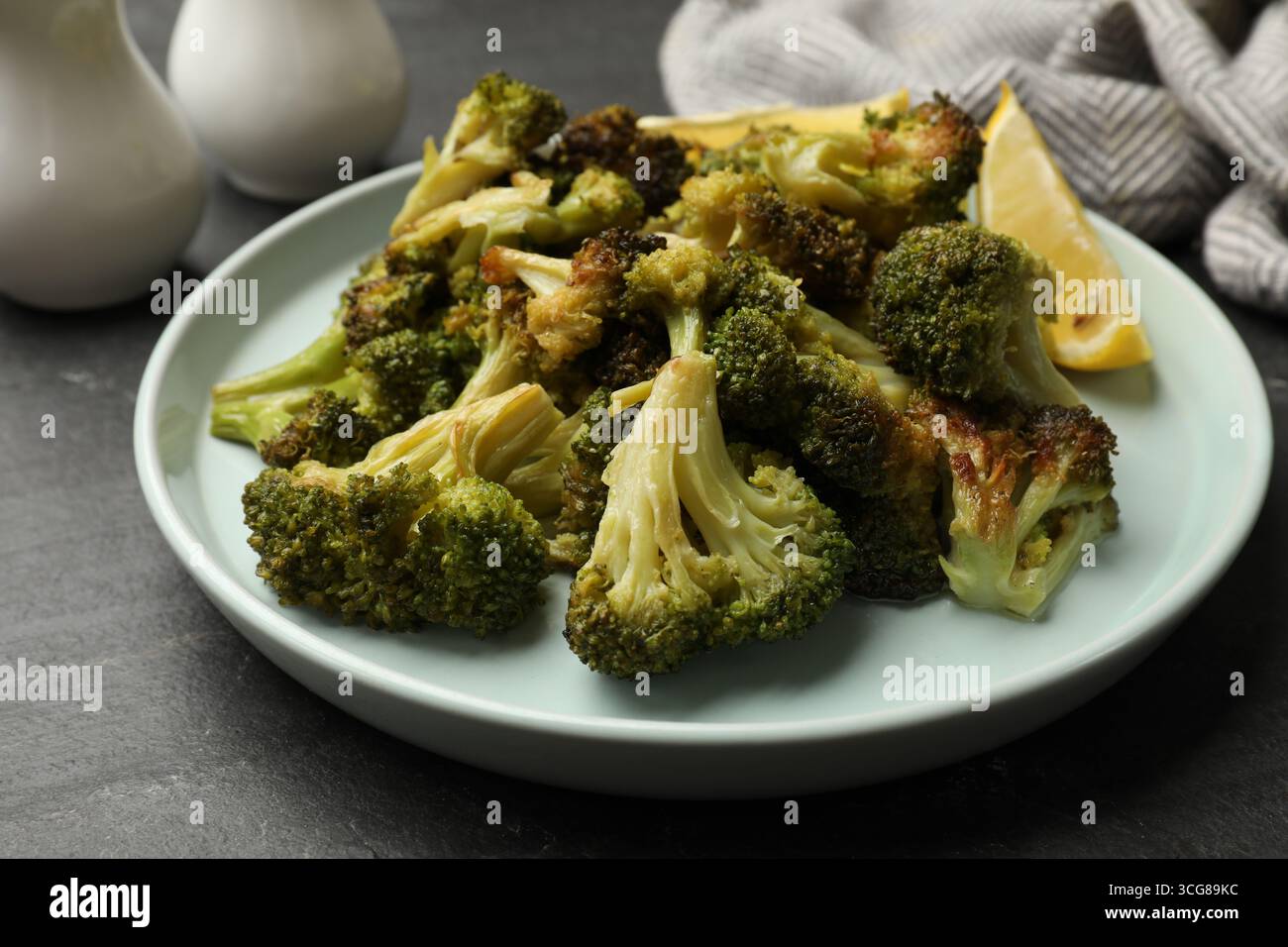 Savoureux brocoli frit et citron sur la table noire, gros plan Banque D'Images