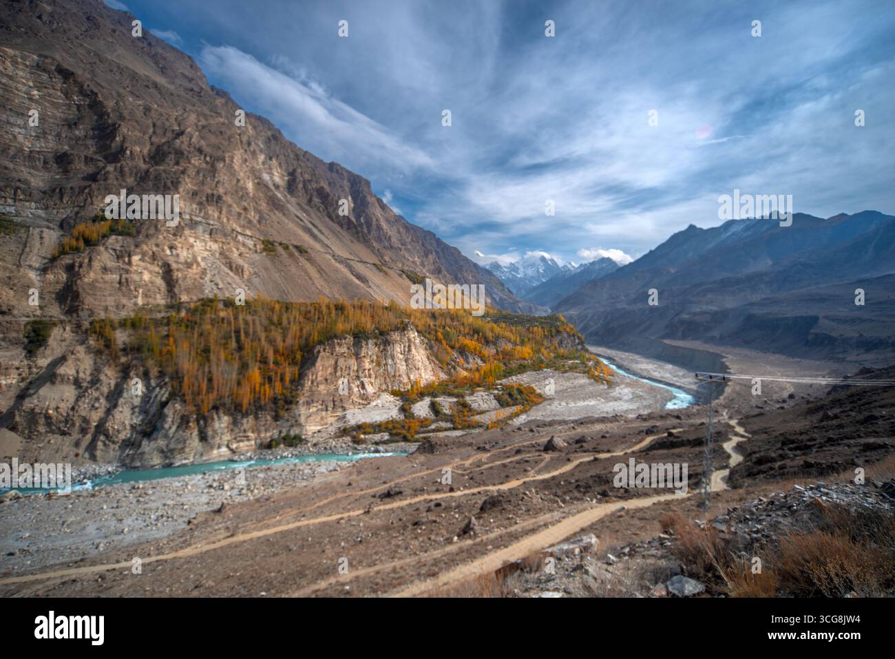 Vue sur les sculptures de la rivière turquoise à travers la vallée rocheuse accidentée, avec des arbres d'automne accrochés aux falaises et des sommets enneigés au loin, H. Banque D'Images