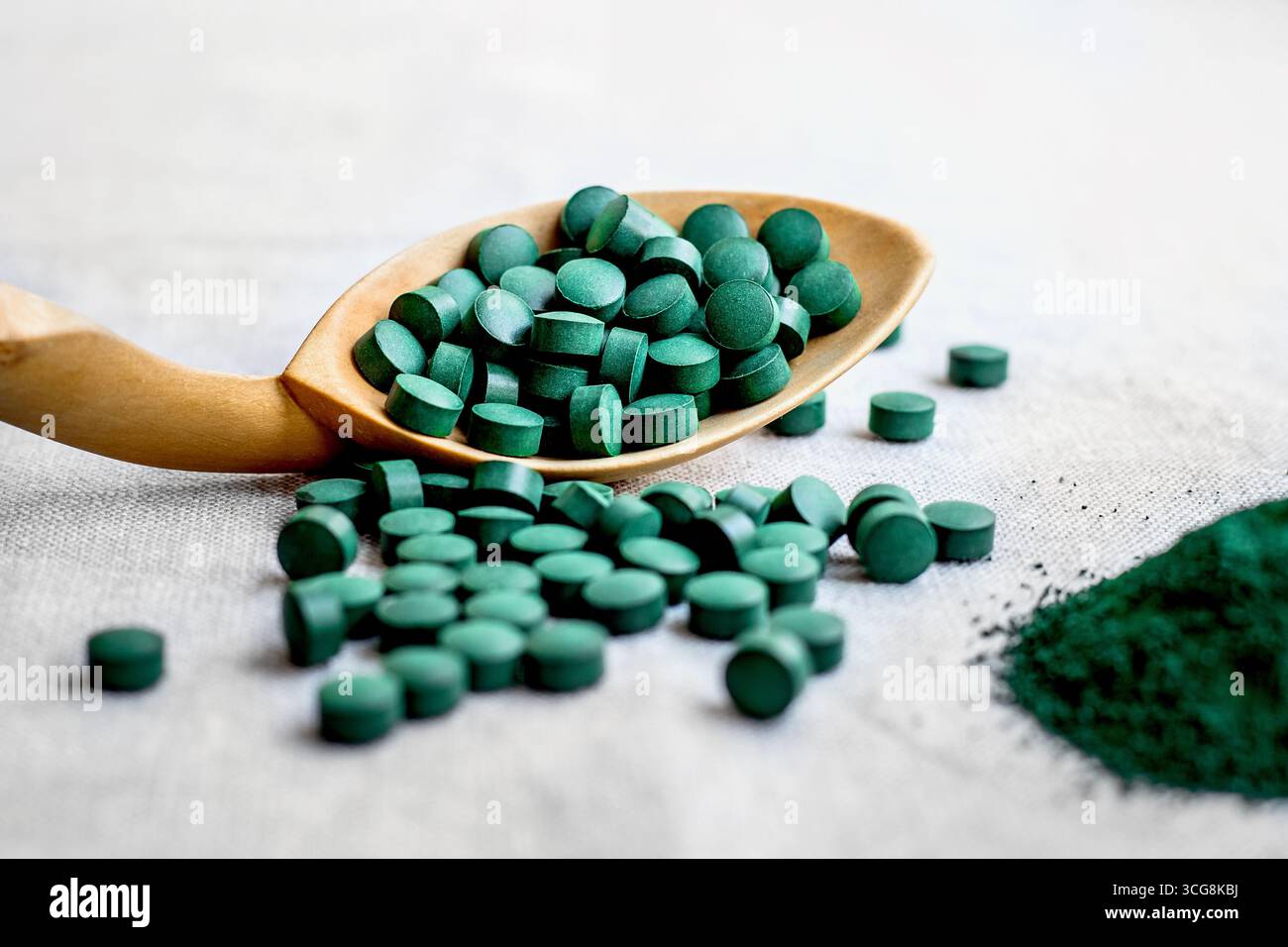 Pilules de spiruline d'algue, chlorella sur une cuillère en bois gros plan. Super aliment végétarien avec des protéines végétales sur fond clair Banque D'Images