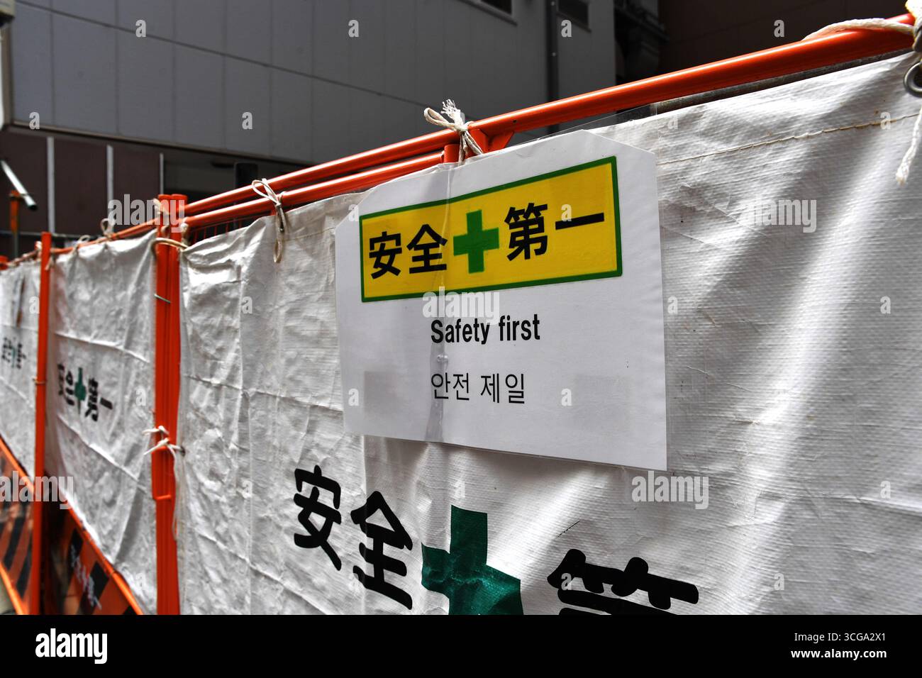 une barrière de sécurité standard pour les chantiers au Japon avec un panneau multilingue „Sécurité d'abord“ - Tokyo - Japon Banque D'Images