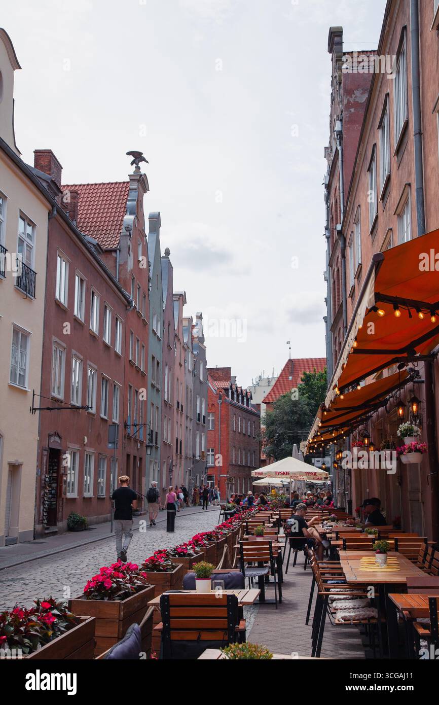 Gdansk, Pologne - 04-07-2025 - tables d'un café d'été situé dans la vieille ville avec des bâtiments historiques Banque D'Images