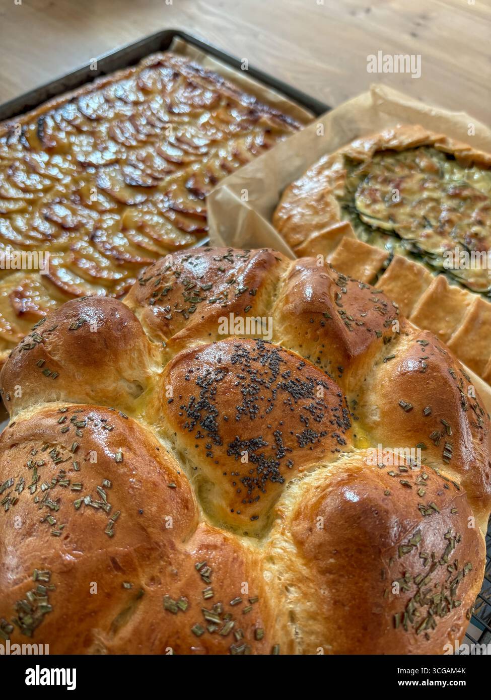 Rond Partager et déchirer pain traditionnel juif Challah cuit à la maison, présenté sur un plateau métallique. Il est garni de graines de pavot et de romarin frais. Banque D'Images