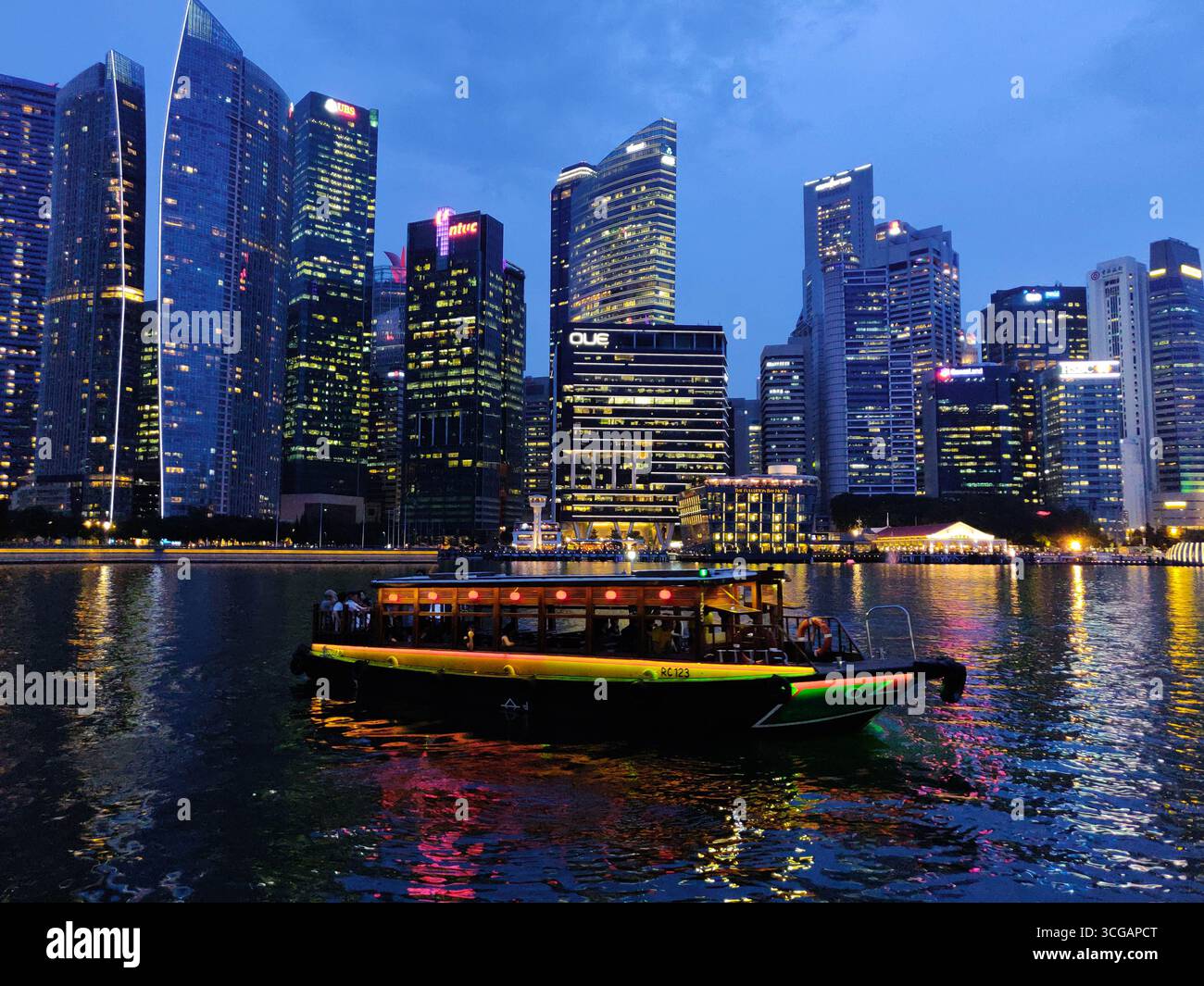 Panorama pittoresque de Singapour après le coucher du soleil avec gratte-ciel illuminés et bateaux sur l'eau Banque D'Images
