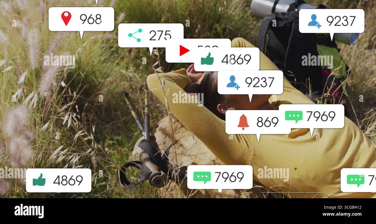 Femme inclinée regardant les icônes de notification flottant dans les hautes herbes, avec sac à dos et bâtons de randonnée Banque D'Images