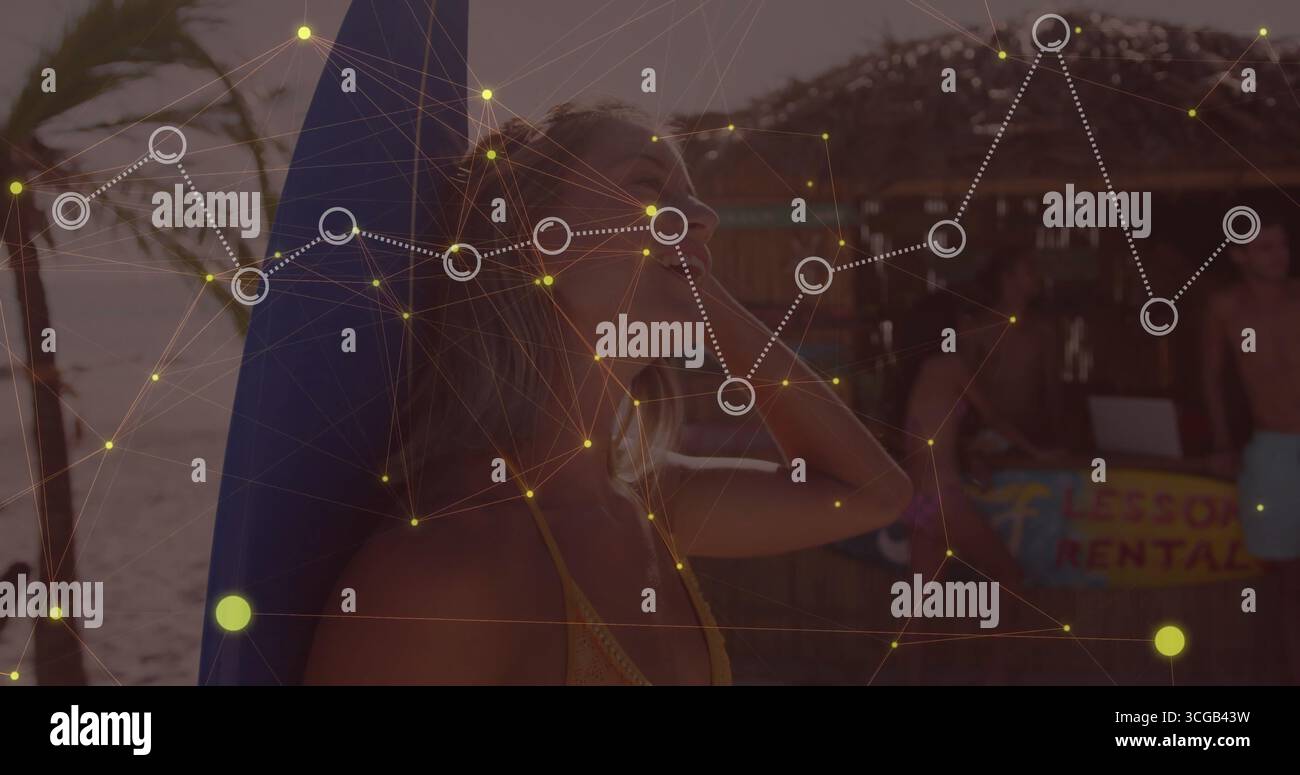 Femme en bikini appuyée contre la planche de surf à la cabane de location de plage, homme torse tapant sur ordinateur portable Banque D'Images